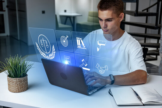 Young man working on laptop with holographic screen in modern workspace setting