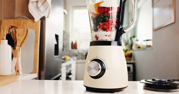Fruits, blender and table for smoothie in kitchen for healthy drink, protein shake and nutrition. Machine, counter and organic ingredients for weight loss, diet milkshake and detox benefits at house - Powered by Adobe