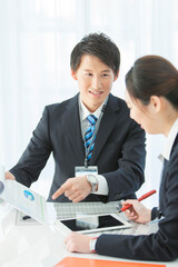 資料を見せて打ち合わせをするビジネスマンとビジネスウーマン 