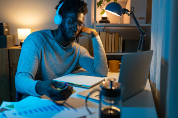 Young African American college student studying at home late at night.
