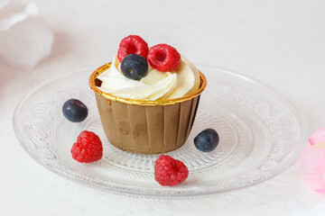 Cupcake au chocolat blanc avec fruits rouges (myrtilles et framboises), fait maison, pâtisserie gourmande sur une table en marbre