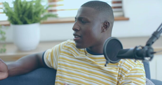 Recording man wearing yellow and white striped T-shirt speaking into black mic in living room - Powered by Adobe