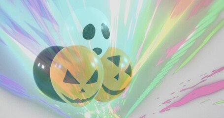 Floating Halloween balloons showing two orange pumpkin faces and white ghost in studio, pastel rays
