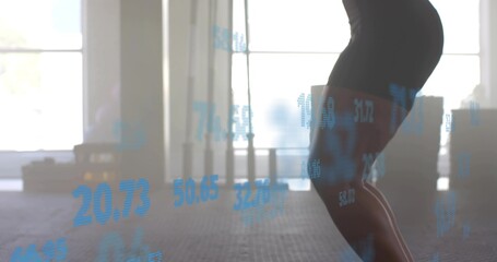 Squatting woman in black shorts lowering hips in gym with rubber floor, data overlay, copy space