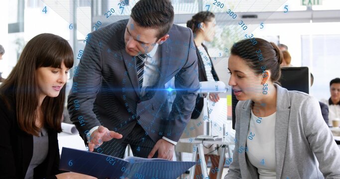 Leaning man in suit pointing at blue folder while team reviewing digital overlay in modern office