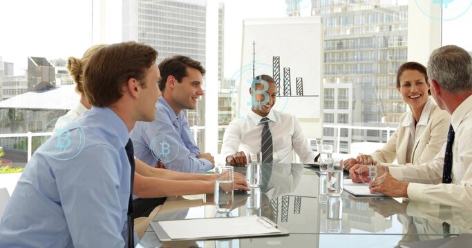 Discussing seven staff sitting at glass table in office in suits with flipchart and Bitcoin icons