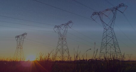 Obraz premium Silhouetting three high-voltage towers and power lines over rural field at sunset with tall grasses