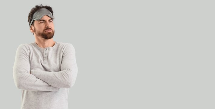 Sleepy man in pajamas on light background with space for text - Powered by Adobe