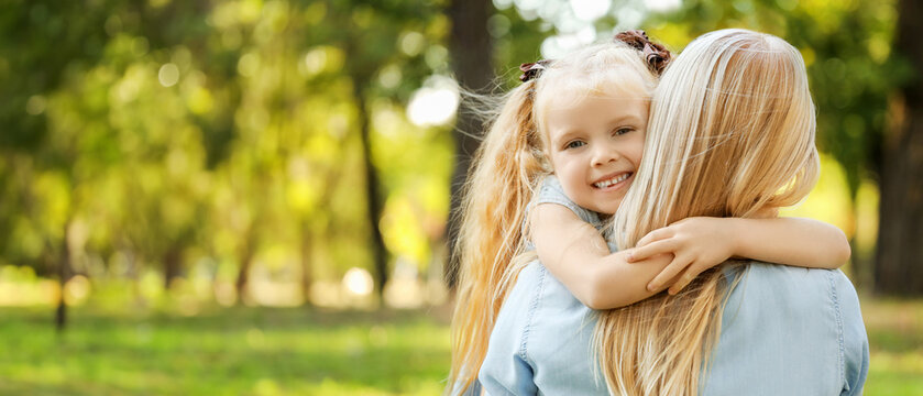 Happy mother with her little daughter hugging in park, closeup
