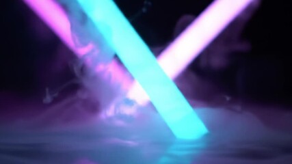 Two light sabers crossing in the dark with smoke.