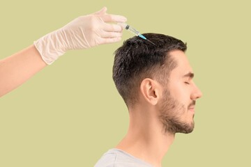 Fototapeta premium Young man with dandruff receiving injection for hair growth on color background