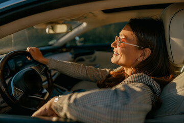 Woman enjoying sunlight and serene pause, eyes closed with relaxed posture while parked, warm glow and calm interior emphasize