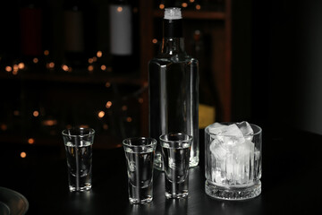 Shots of cold vodka and ice cubes on table in bar