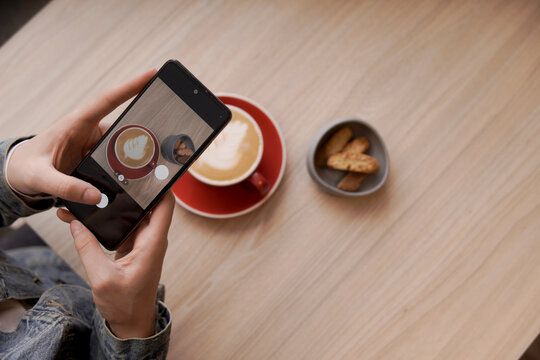 Person taking picture of coffee and cookies with phone