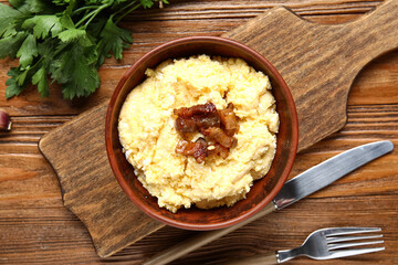 Bowl of tasty banosh on wooden background