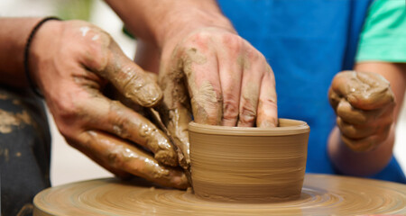 Potter's hands skillfully shaping clay on a pottery wheel, with a child's hand gently assisting in the background, creating a warm and engaging atmosphere of creativity and learning