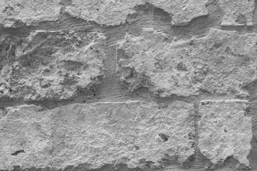 Textured gray stone wall with rough surface and uneven bricks in a rustic style showcasing natural stone patterns