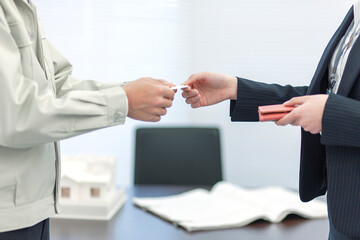 名刺交換する作業着姿の男性とビジネスウーマン 