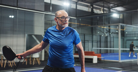 Padel, sports and senior man for game, tournament and competition on indoor court. Tennis club, athlete and person with racket for training, exercise and workout for challenge, practice and fitness