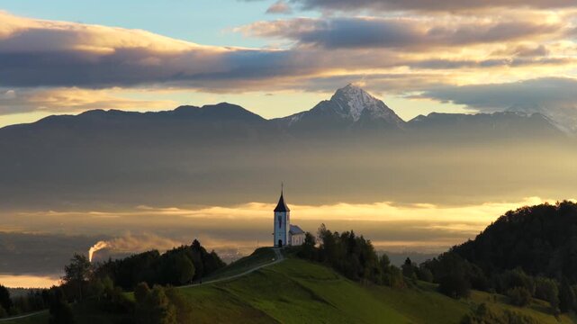 Aerial view of Slovenia's Jamnik church with Alps at sunrise