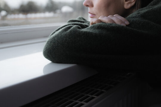 Thoughtful sad woman sitting on a windowsill. Mental health and seasonal disorder. Winter scenery outside - Powered by Adobe