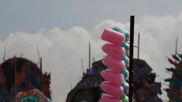 Bags of pink and blue cotton candy hang beside giant colorful kites in Sumpango Guatemala