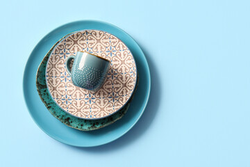 Plate, bowl, saucer and cup on blue background. Top view