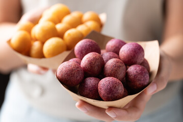 Deep fried sweet potato balls in paper bowl holding by hand, Thai street food snack