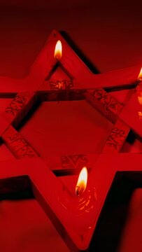 Vertical video: Reacting to draft, three candles dripping wax on hexagram holder flickering in dark