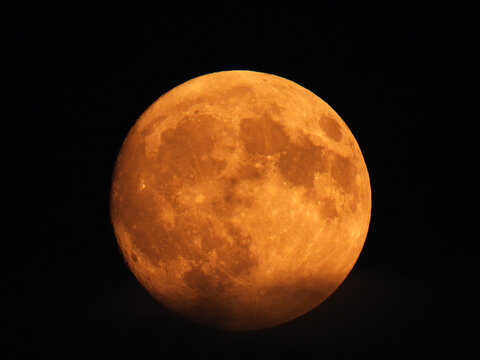 blurred full moon in the dark sky behind clouds