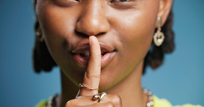 Hush, mouth and secret with black woman in studio for gossip, silence or whisper gesture. Emoji, finger on lips and quiet with African person on blue background for confidential, mystery or privacy - Powered by Adobe