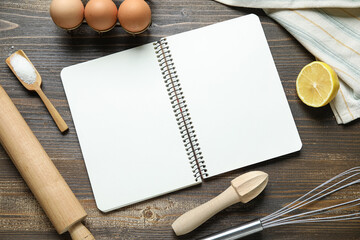 Composition with blank recipe book, kitchen utensils and ingredients on wooden background