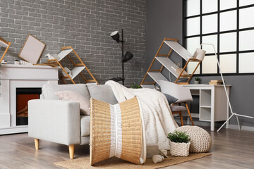 Naklejka premium Interior of messy living room with grey sofa and overturned furniture after earthquake