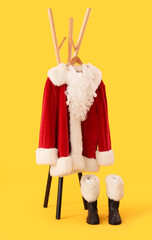 Rack with Santa costume on yellow background