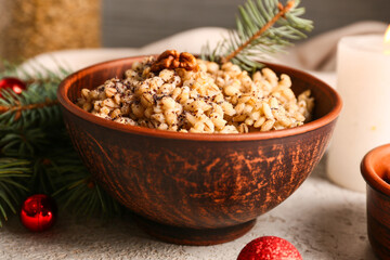 Bowl of traditional Ukrainian Kutya dish with fir branches and Christmas balls on white table, closeup