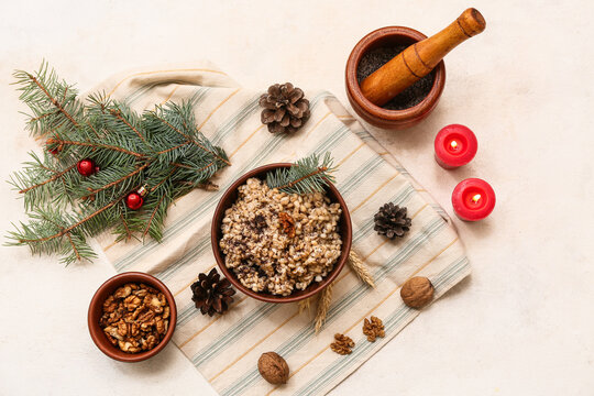 Bowl of traditional Ukrainian Kutya dish with Christmas tree branches and burning candles on white background