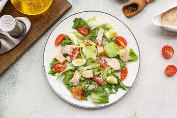 Plate with tasty chicken Caesar salad on grunge background