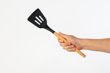 Hand holding kitchen utensils on white background