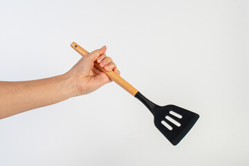 Hand holding kitchen utensils on white background