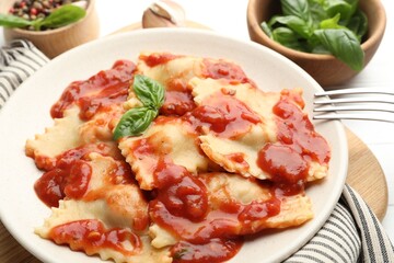 Delicious ravioli with tomato sauce and basil served on white wooden table, closeup