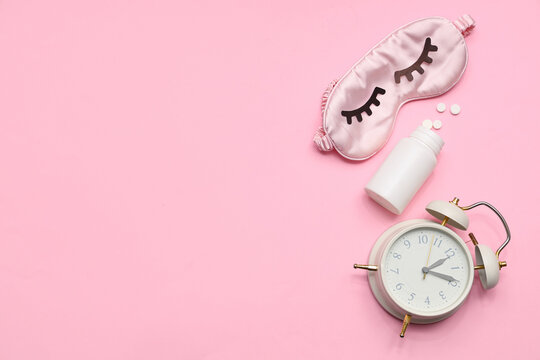Alarm clock with sleeping mask and pills on pink background. Melatonin concept