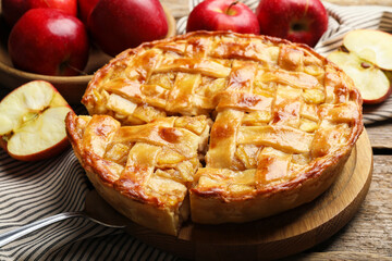 Delicious homemade pie and apples on wooden table, closeup