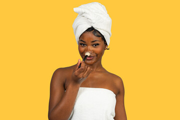 Young black woman applying makeup powder with brush