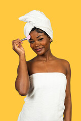 Young black woman applying makeup powder with brush