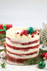Delicious sponge cake with Christmas decor and red currants on white marble table against grey background, closeup