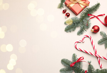 Fir tree branches, candy canes and Christmas decor on light background, flat lay with bokeh effect. Space for text