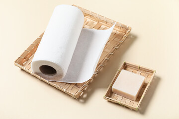 Wicker basket with roll of paper towels and soap on beige background