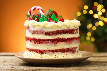 Tasty cake with Christmas decor on wooden table against blurred lights, closeup