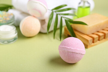 Bath bombs, cosmetic products and towel on green background