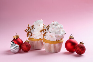 Tasty cupcakes with Christmas decor on pale pink background, closeup